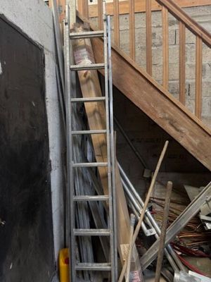 une échelle appuyée contre un mur, à côté d'un tas de vieilleries