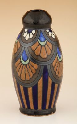 un vase bleu et brun posé sur une surface blanche