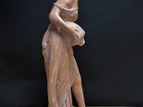 statue of a woman holding a vase on a table with a black background