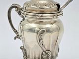 une théière ancienne en argent avec une cuillère, sur fond blanc