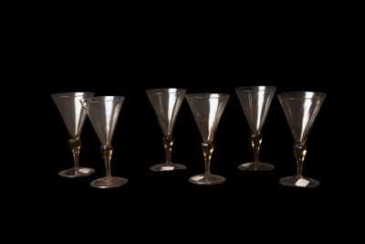 quatre verres à vin sont alignés sur un fond noir