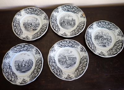 four plates with black and white designs on them on a wooden table