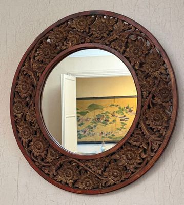 a round mirror hanging on the wall above a sink