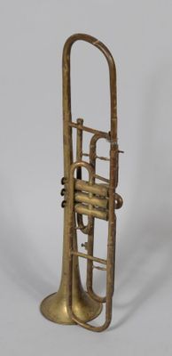 an old brass trumpet sitting on top of a white surface