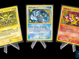 Trois cartes Pokémon sont représentées en rangée sur un fond noir