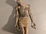 statue d'un homme tenant un couteau à la main, posée sur une surface grise