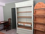a white bookcase and a wooden desk in the corner of a room