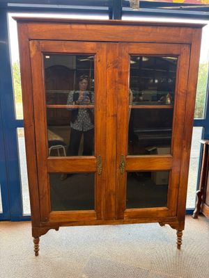 une grande armoire en bois avec des portes vitrées dans la pièce