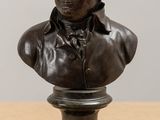 bronze bust of a man on a pedestal on a wooden table