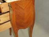 a small wooden table with a marble top next to a drawer