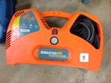 an orange and black air compressor sitting on top of a cement floor