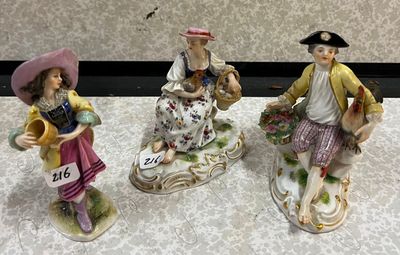 trois figurines représentant des personnes sont posées sur une table