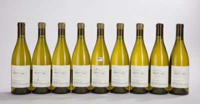 six bottles of white wine lined up in a row on a white surface
