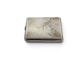 an antique silver cigarette case with bamboos on it on a white surface