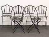 four black metal folding chairs sitting next to each other in a room