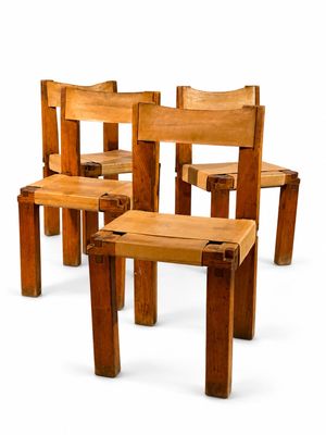 quatre chaises en bois disposées les unes à côté des autres sur une surface blanche