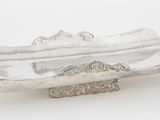 une assiette en argent sur laquelle est représenté un bateau, sur un fond blanc