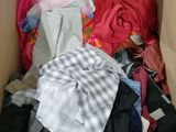 une boîte en carton remplie de vêtements, ainsi que des vêtements éparpillés sur le sol