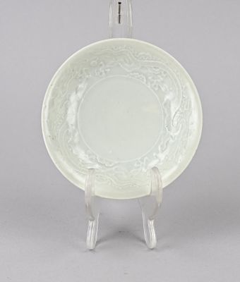 une photo d'une assiette blanche posée sur un support, sur une surface grise