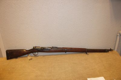 Un vieux fusil est posé sur une table près d'un mur.