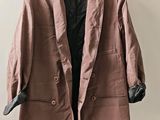 une veste marron suspendue à un cintre accroché au mur