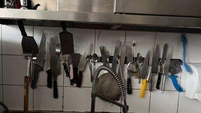 a lot of knives hanging on the wall in the kitchen