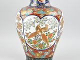 a vase with a bird on it sitting on a table