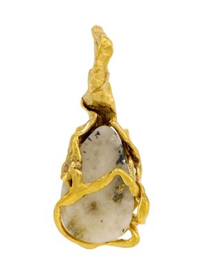 a close up of a gold plated pendant with a white stone