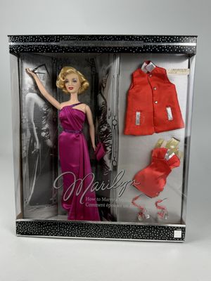 La poupée Barbie porte une robe rouge et un manteau rouge.