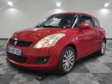 the red suzuki swift is parked on a checkered floor