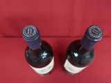 two bottles of wine sitting on a red cloth