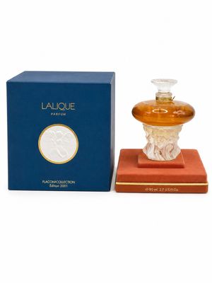 un flacon de parfum posé à côté d'une boîte sur une surface blanche