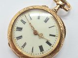 a gold pocket watch with roman numerals on it
