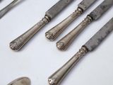 five silver spoons and two silver spoons on a white table