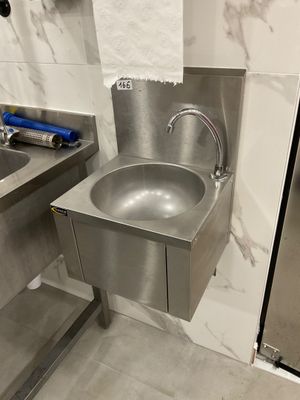 a stainless steel sink in the corner of a bathroom