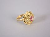 un gros plan d'une bague en or ornée d'une pierre rose au centre