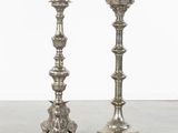 pair of silver candlesticks on a table with a white wall in the background