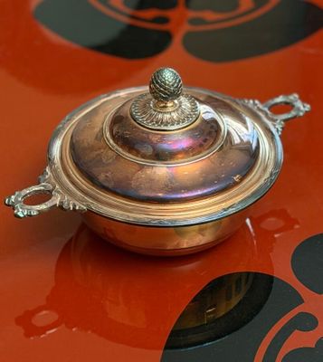 a silver plate with a lid sitting on a red table