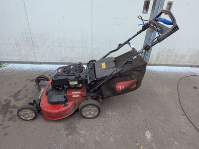 une photo d'une tondeuse à gazon garée devant un garage