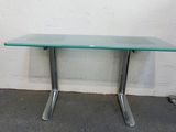 une table en verre avec des pieds en métal et un plateau en verre