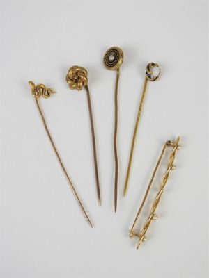 quatre épingles à cheveux dorées et une broche posées sur un fond blanc