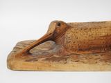 carved wood sculpture of a bird with a long beak on a piece of wood