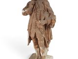 an old statue of a man with a hat and a coat