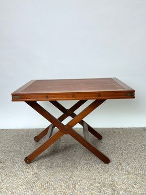 une table en bois aux deux pieds entrecroisés, posée sur un sol recouvert de moquette