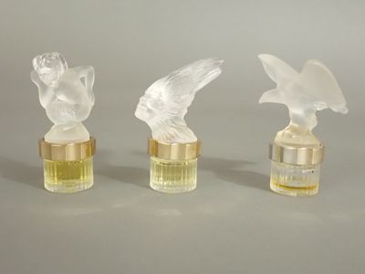 trois oiseaux en verre transparent posés sur une bouteille en verre