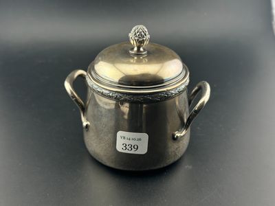 un petit pot en argent avec un couvercle, posé sur une table