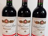 trois bouteilles de vin rouge sont alignées sur une surface blanche