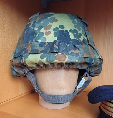 un casque posé sur une étagère, avec un chapeau posé dessus