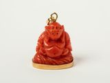 une image représentant une petite statuette de Bouddha rouge posée sur un socle plaqué or