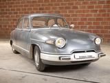 a silver car that is parked in front of a brick wall
